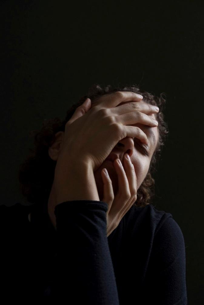 woman wearing blue long-sleeved shirt touching her face